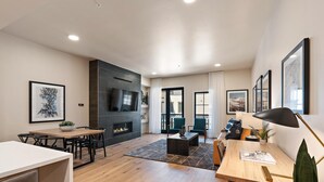 Una sala moderna con chimenea, comedor y zona de estar con vistas al exterior.