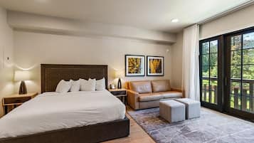 A modern bedroom with a large bed, a leather sofa, and a view through a glass door.