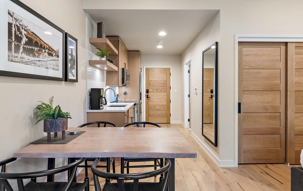 Una cocina moderna con mostrador de madera, un fregadero y un microondas. En primer plano, hay una mesa de comedor con sillas.