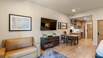 A modern living room with a sofa, a coffee table, a TV, and a dining area with a table and chairs.
