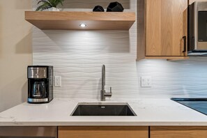 A kitchen with a built-in sink, a coffee maker, and wooden cabinets. - Makin Memories | Includes Two 1-Day Lift Tickets (Tamarack)