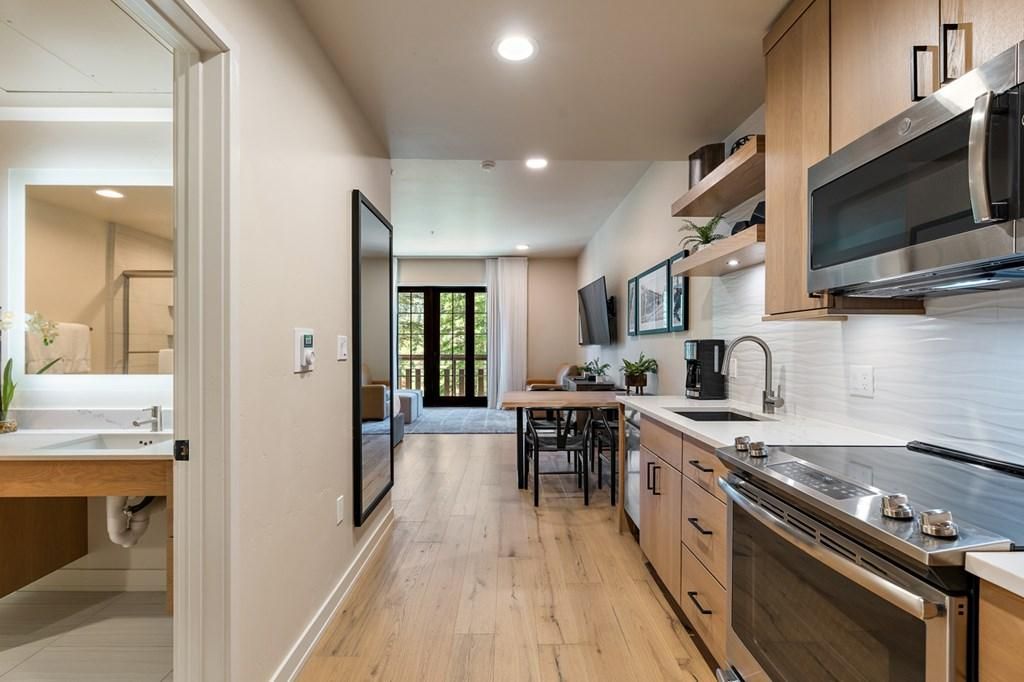 A modern kitchen with a wooden countertop, stainless steel appliances, and a dining area with a table and chairs.