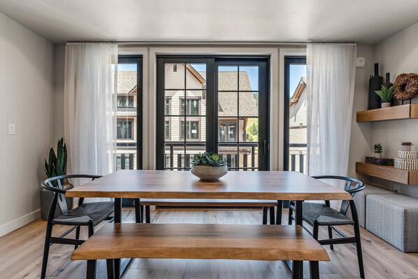 A dining area with a wooden table, two chairs, a bench, and a potted plant. - Sassafras Suite | Includes Two 1-Day Lift Tickets (Tamarack)