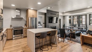 A modern kitchen with a central island, stainless steel appliances, and a dining area with a view. - Sassafras Suite | Includes Two 1-Day Lift Tickets (Tamarack)