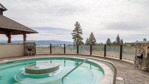 Una piscina con diseño circular, rodeada de muros de piedra y barandilla de vidrio.