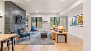 A spacious living room with a fireplace, seating area, and large windows. - Mountain Condo | Includes Two 1-Day Lift Tickets (Tamarack)