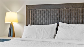 A hotel room with a bed, white bedding, a grey headboard, and a lamp on the nightstand. - Mountain Condo | Includes Two 1-Day Lift Tickets (Tamarack)