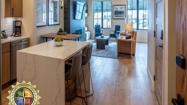 Una cocina amplia con una isla de mármol, armarios de madera y un comedor con sofá y mesa de centro.
