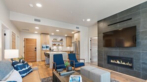 A modern living room with a fireplace, a sofa, a coffee table, and a TV mounted on the wall.