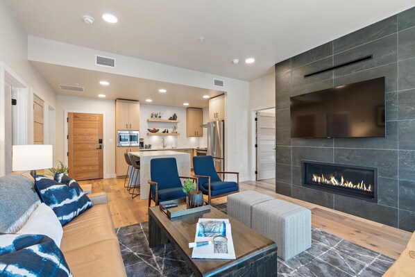 A modern living room with a fireplace, a sofa, a coffee table, and a TV mounted on the wall.