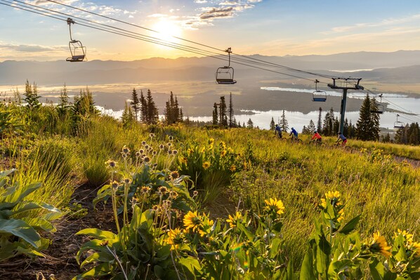 A mountain landscape with a lake, ski lifts, and greenery.