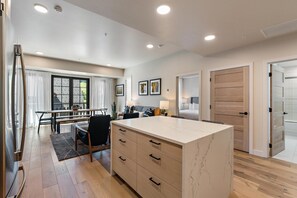 A modern kitchen with a marble countertop, wooden cabinets, and a dining area with a table and chairs.