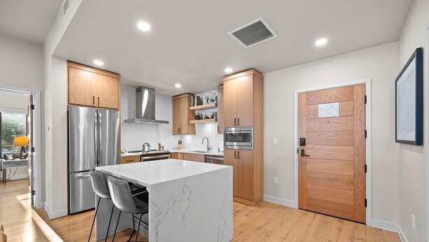 Una cocina moderna con electrodomésticos de acero inoxidable, armarios de madera y una isla de mármol.
