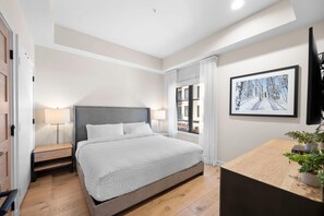 Une chambre moderne avec un grand lit, des tables de chevet, un bureau et une fenêtre avec des rideaux.