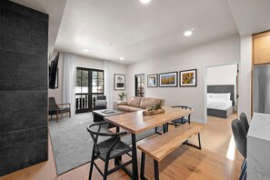 Un salon moderne avec une table à manger en bois, un canapé en cuir et une grande fenêtre.