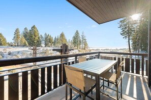 A balcony with a table and chairs, overlooking a snowy landscape with trees. - Night in Paradise | Includes Two 1-Day Lift Tickets (Tamarack)