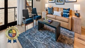 Un salon comprenant un canapé, deux fauteuils, une table basse et une grande fenêtre donnant sur un paysage montagneux.
