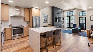 Une cuisine moderne dotée d’un îlot central, d’appareils électroménagers en acier inoxydable et de meubles de rangement en bois.