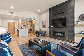 Una sala de estar moderna con chimenea, un comedor y una cocina al fondo.