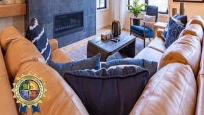 Un salon moderne doté d’une cheminée, de canapés en cuir, d’une table basse et d’une grande fenêtre offrant une vue sur les arbres.