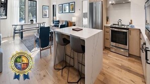 Una cocina moderna con una isla de mármol, electrodomésticos de acero inoxidable y un comedor con vistas.