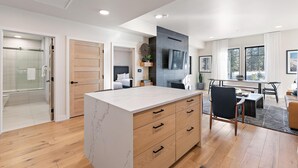 Una cocina moderna con encimera de mármol, armarios de madera y un comedor con mesa y sillas.