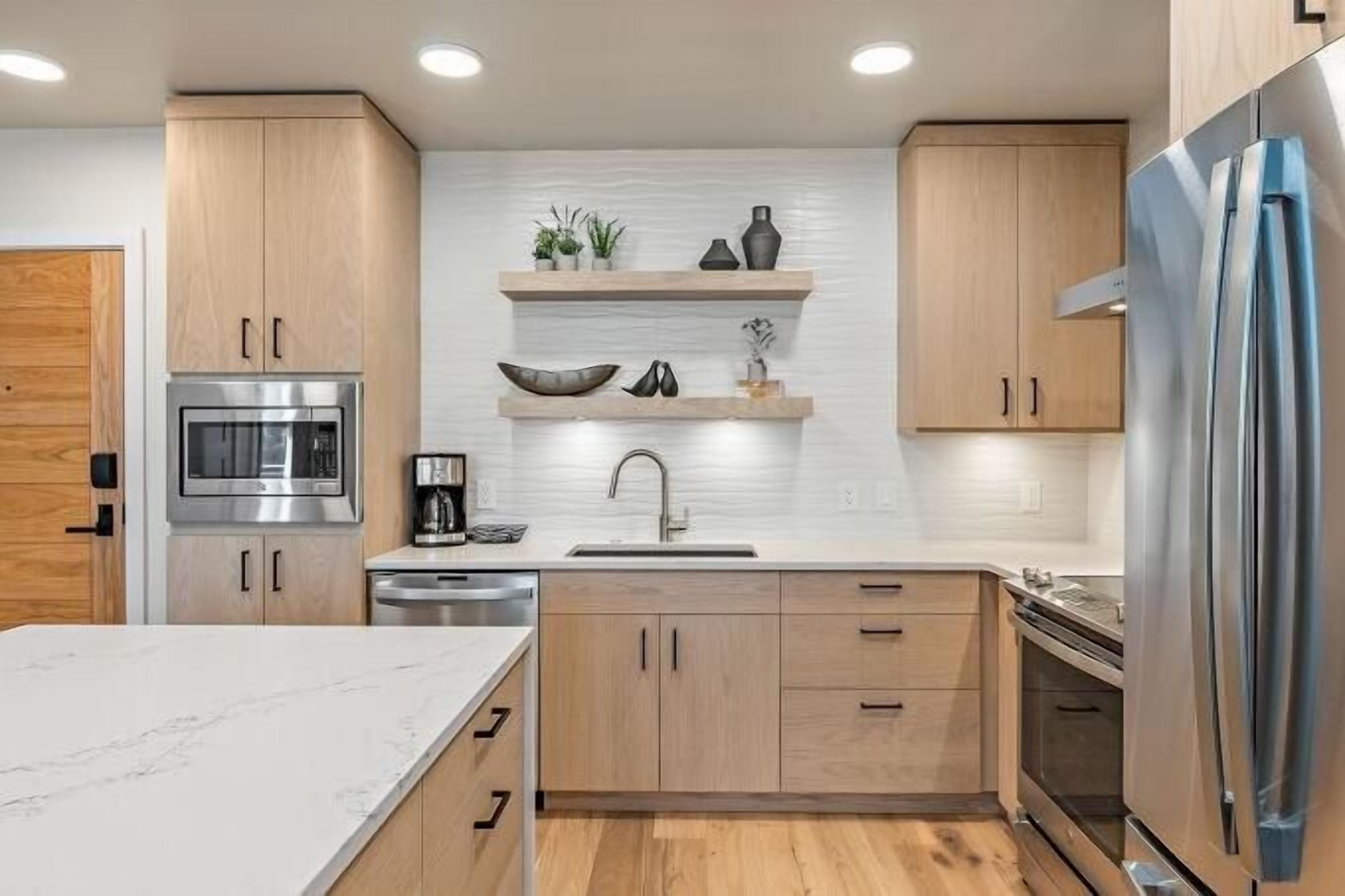 Une cuisine moderne avec des meubles en bois, un réfrigérateur en acier inoxydable et un four encastré.