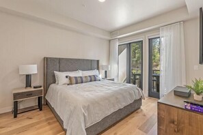 Un dormitorio con cama, mesitas de noche, un escritorio y vistas al exterior.