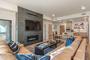 A modern living room with a fireplace, leather sofa, and a dining area. - Scarlet Tanager | Includes Two 1-Day Lift Tickets (Tamarack)