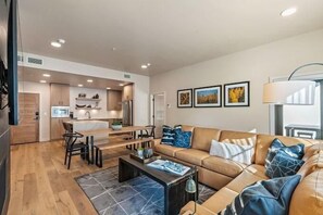 Ein modernes Wohnzimmer mit einer Couch, einem Couchtisch und einem Essbereich mit Stühlen.