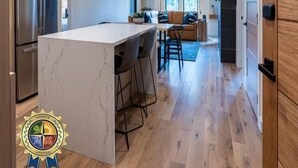 Una cocina moderna con una isla de mármol, armarios de madera y un refrigerador de acero inoxidable.