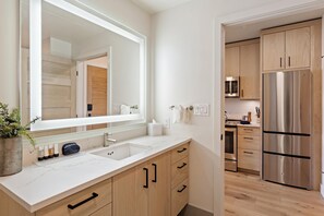 A modern kitchen with a large mirror, stainless steel appliances, and wooden cabinetry.