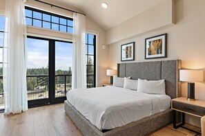 A large bed with white linens, two bedside lamps, and a framed picture on the wall.