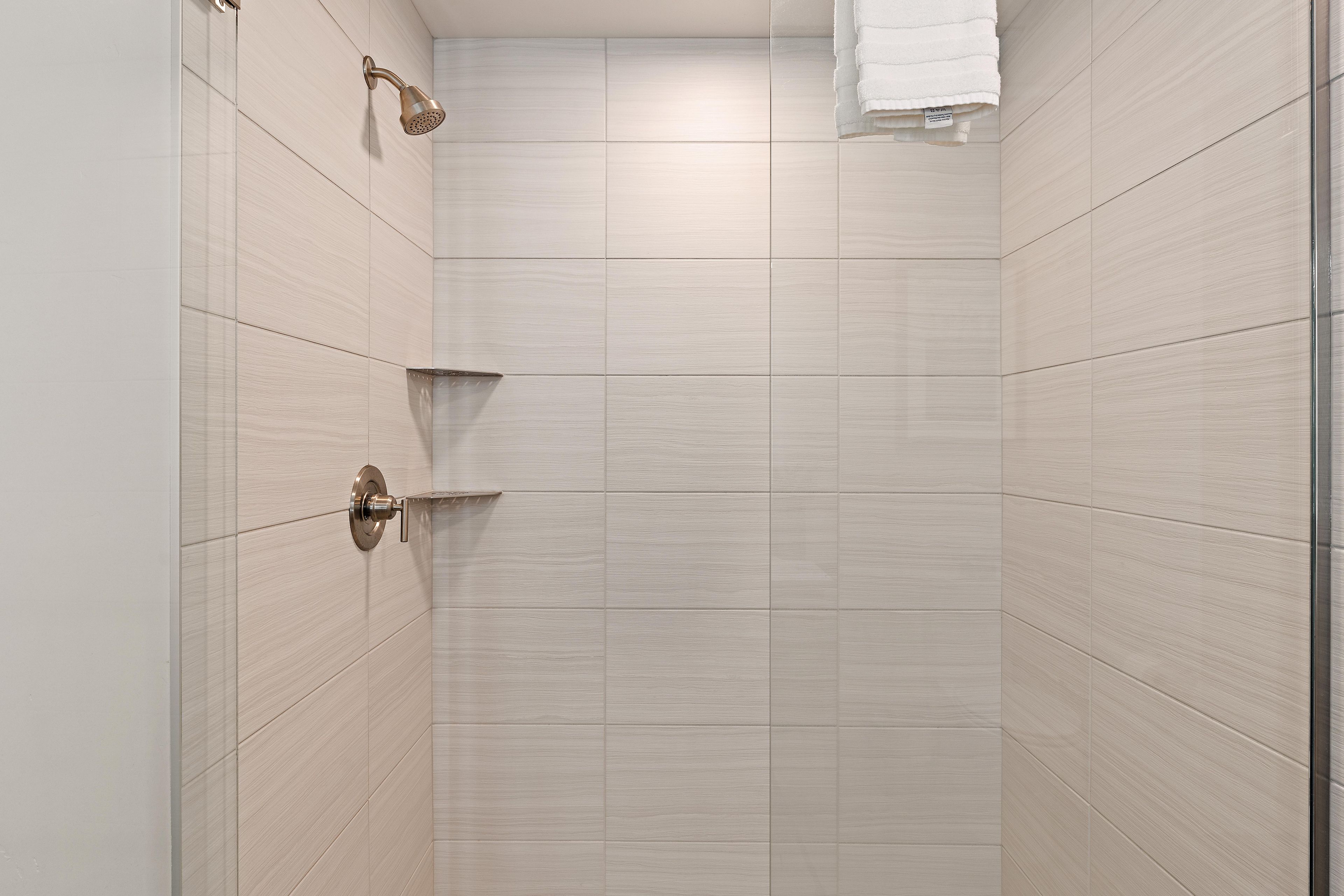 A shower with a handheld showerhead and a wall-mounted faucet.