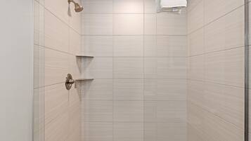 A shower with a handheld showerhead and a wall-mounted faucet.