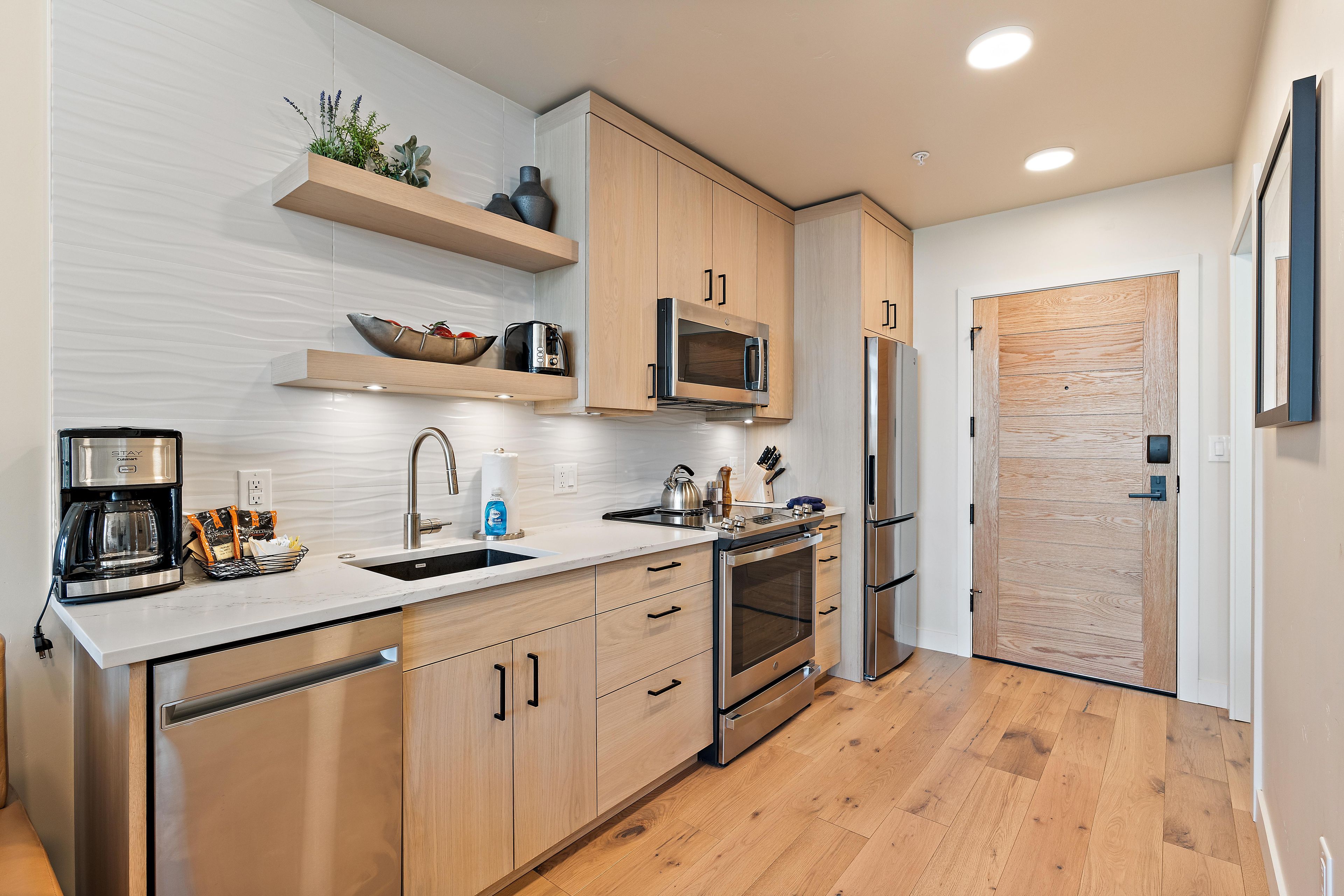 A modern kitchen with wooden cabinets, stainless steel appliances, and a built-in oven.
