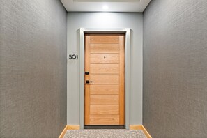 Un couloir avec une porte en bois portant le numéro 501, un mur à texture et une moquette à motifs.