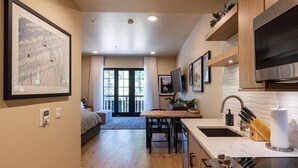 A modern kitchen with a built-in oven, a sink, and a dining area with a table and chairs. - Comfy Condo|Balcony|short stroll to the ski hill (Tamarack)