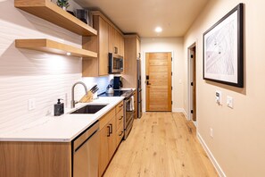 Une cuisine moderne avec des meubles en bois, des appareils en acier inoxydable et un plan de travail en marbre.