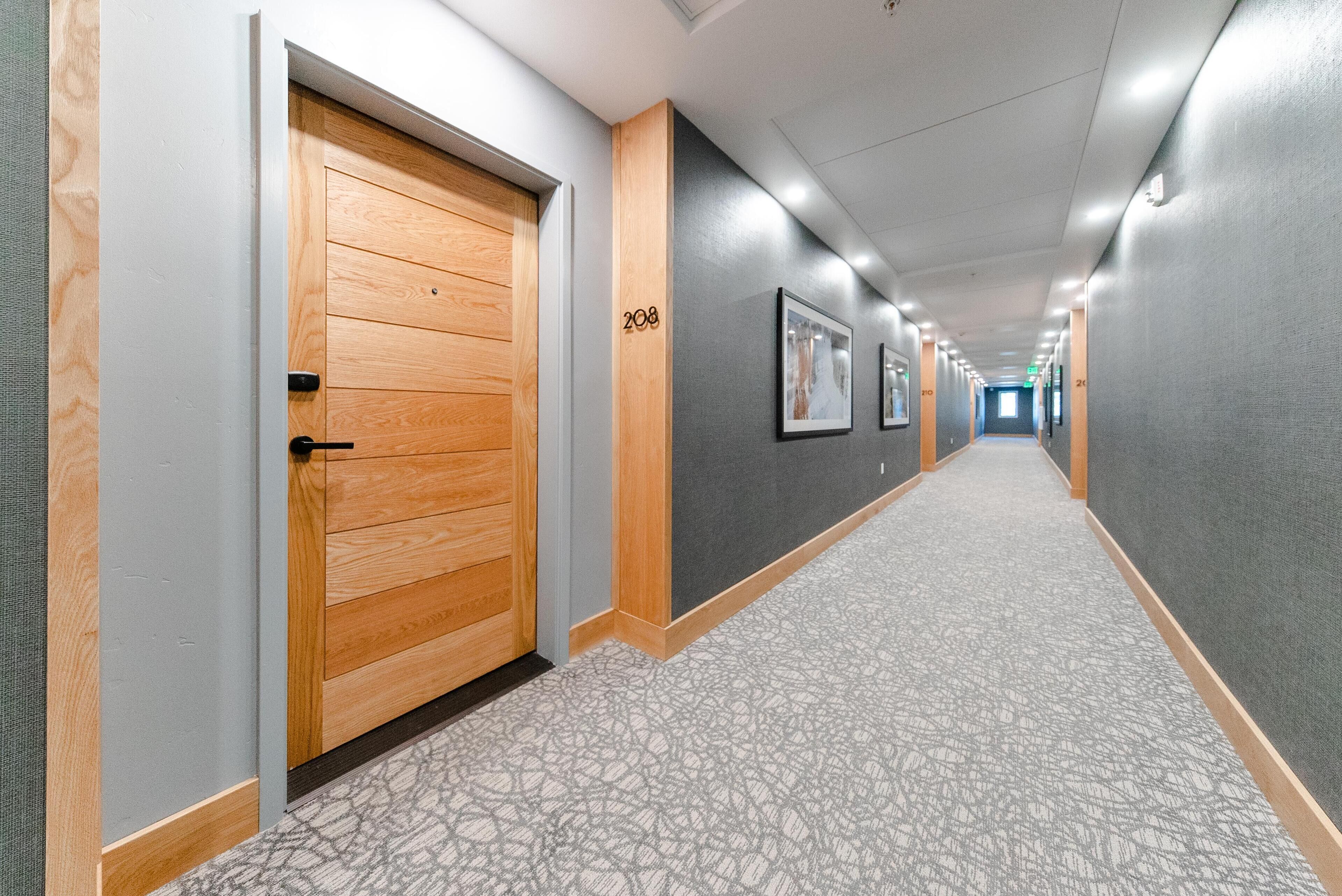 A hallway with wooden doors, numbered 208, and framed pictures on the walls.
