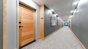 Ein Flur mit Holztüren, der Nummer 208 trägt, und gerahmten Bildern an den Wänden.