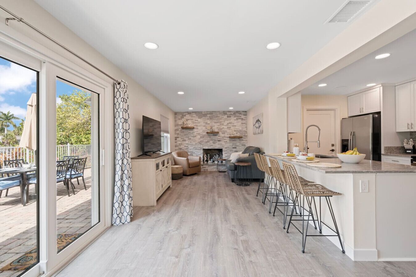 A spacious living area with a fireplace, a dining area with bar stools, and a kitchen with modern appliances.