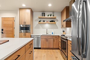 A modern kitchen with wooden cabinets, stainless steel appliances, and a white countertop. - Cloudline | Includes Two 1-Day Lift Tickets (Tamarack)