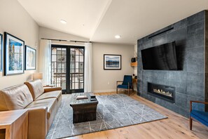 Una sala de estar moderna con chimenea, un sofá, una mesa de centro y un televisor montado en la pared.