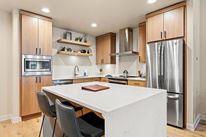 Una cocina moderna con armarios de madera, electrodomésticos de acero inoxidable y encimera de mármol.