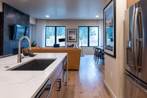 A modern kitchen with a large island, stainless steel appliances, and a dining area with a view of the outdoors.