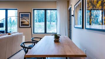 A modern dining area with a wooden table, chairs, and a potted plant.
