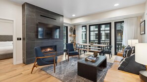 Una sala de estar moderna con chimenea, asientos y un ventanal grande.