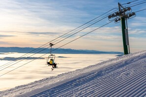 Un télésiège avec des passagers, une pente de montagne enneigée et un ciel dégagé.