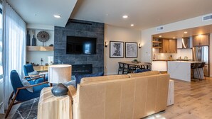 A modern living room with a large beige sofa, a fireplace, and a TV mounted on the wall. - Wind-Walker | Includes Two 1-Day Lift Tickets (Tamarack)